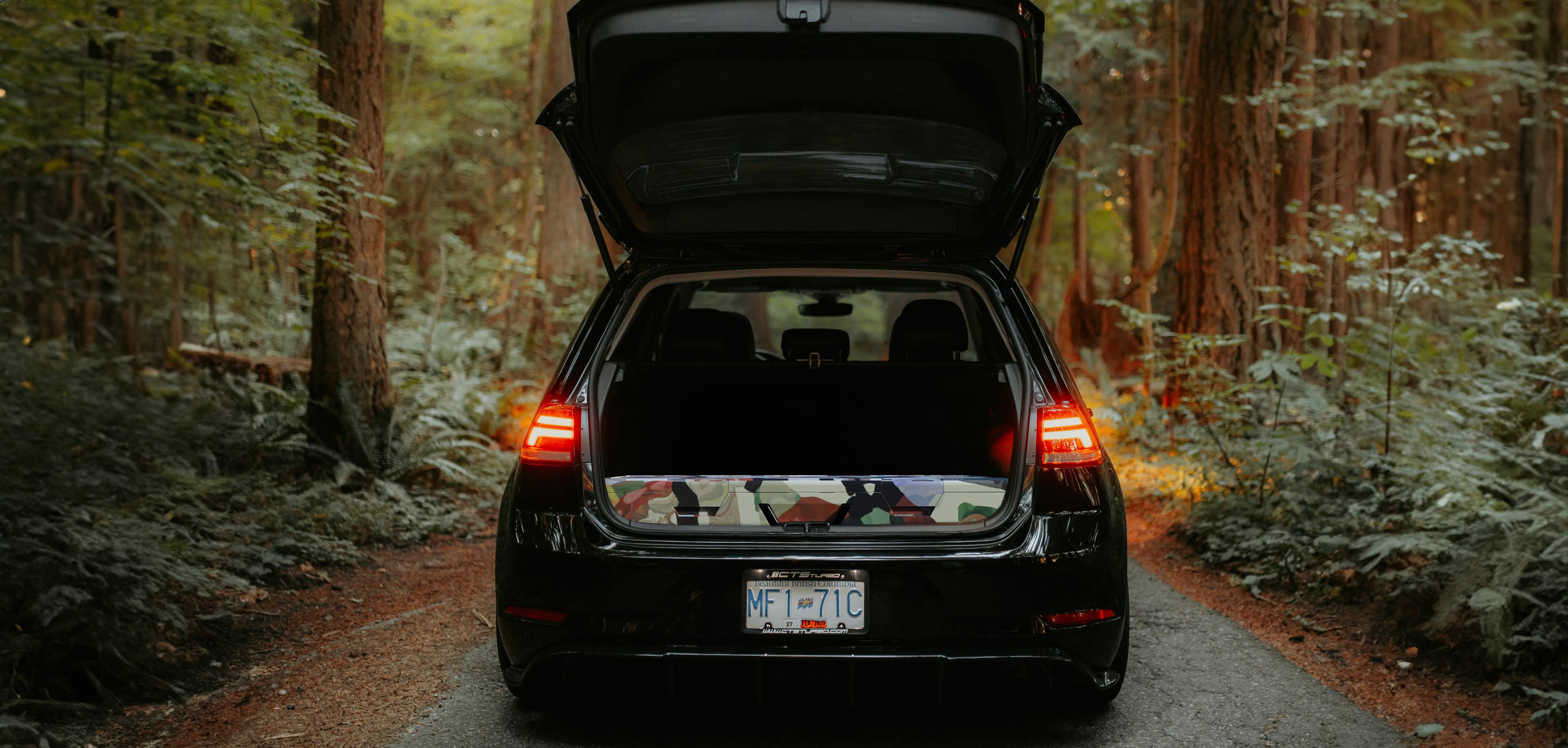 A car with an open trunk outside in the forest. Rest is inside the trunk.