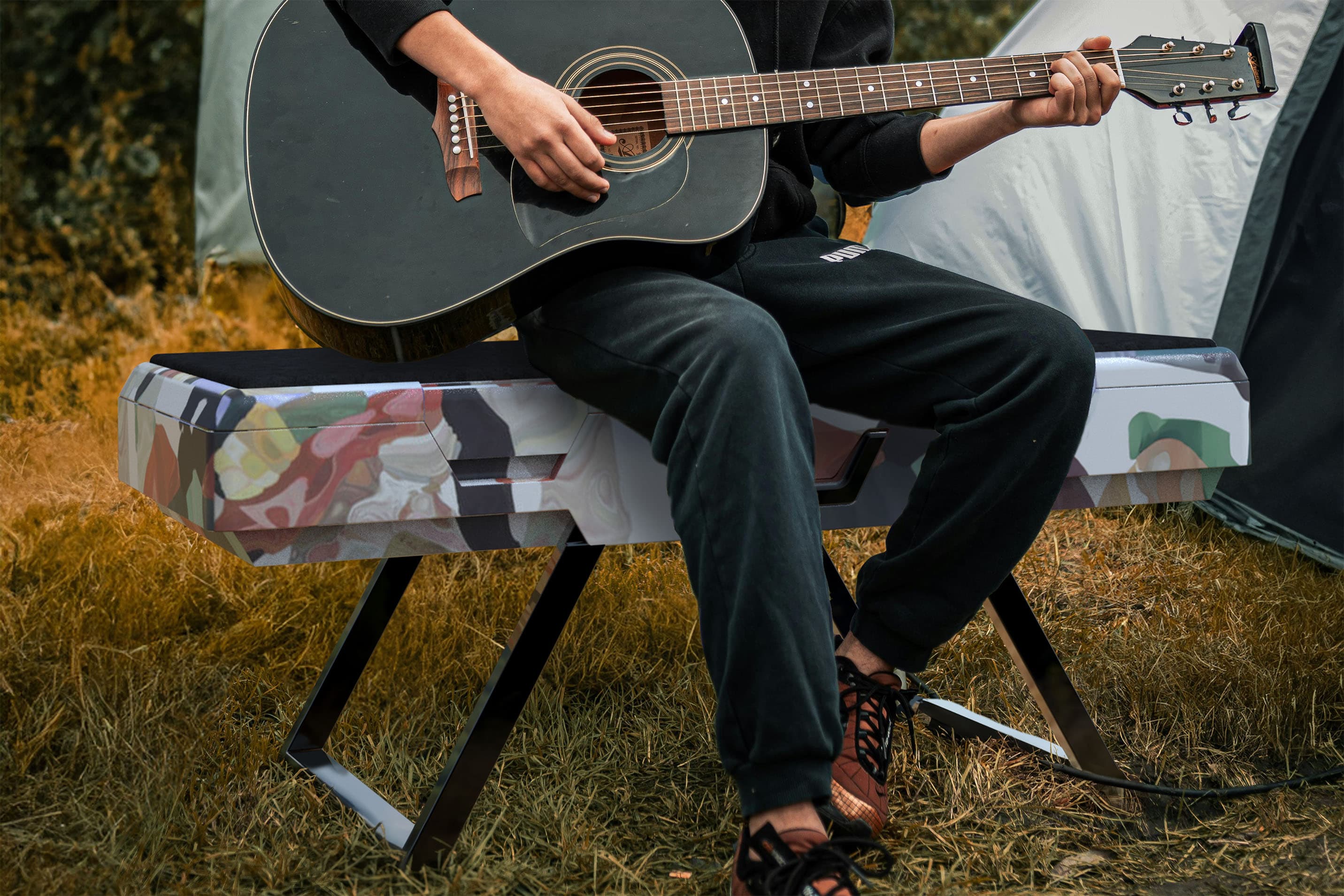 A person sitting playing guitar outside. They are sitting on Rest.